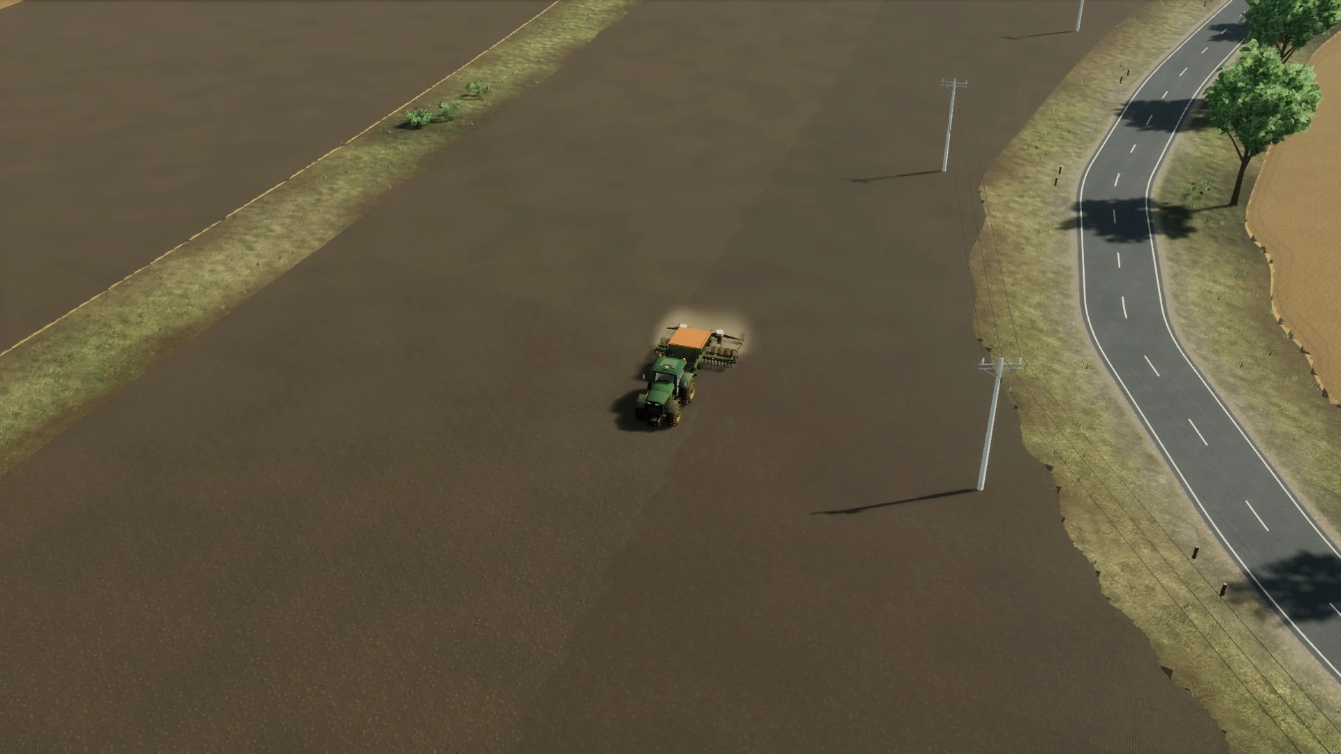 A green tractor works a prepared field with its seed drill lowered.